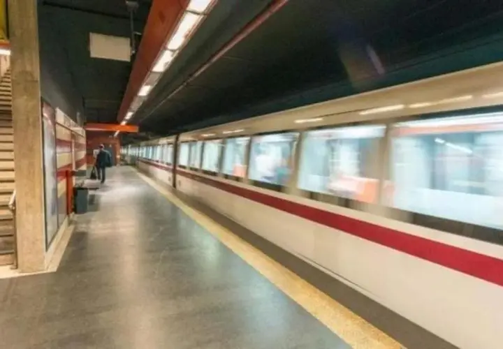 Treno in corsa su binari di una stazione metro. Si intravedono scale e un passeggero in attesa. Le fermate metro a Chiuse sono un luogo di passaggio frenetico.