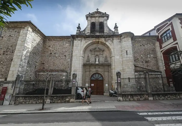 Fachada de la iglesia Consolación en Santander, con una pareja paseando por la acera.