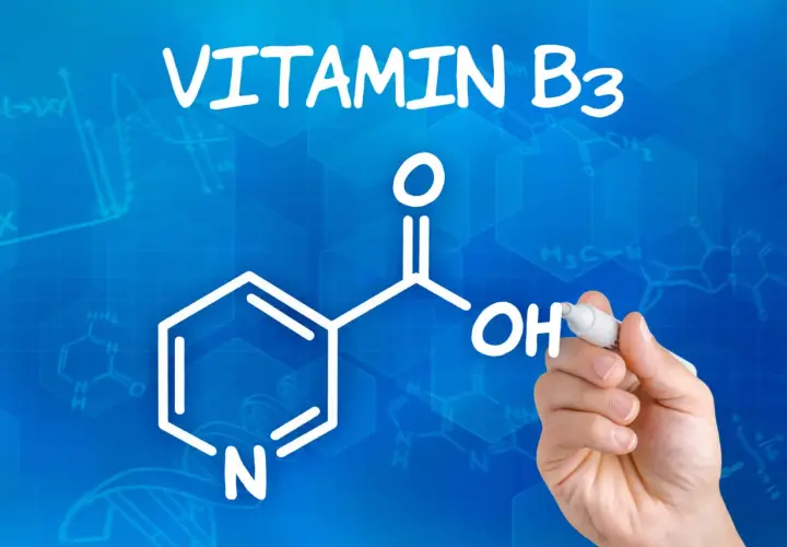 Die chemische Struktur von Vitamin B3, auch bekannt als Niacinamid, wird auf blauem Hintergrund mit Formeln und Graphen gezeichnet.