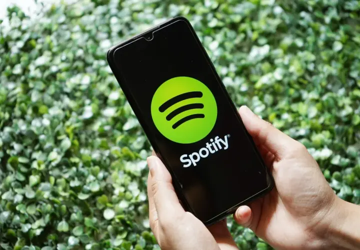 Ręce trzymają smartfon z logo Spotify. Skorzystaj z promocji spotify 3 miesiące za darmo i słuchaj ulubionej muzyki.