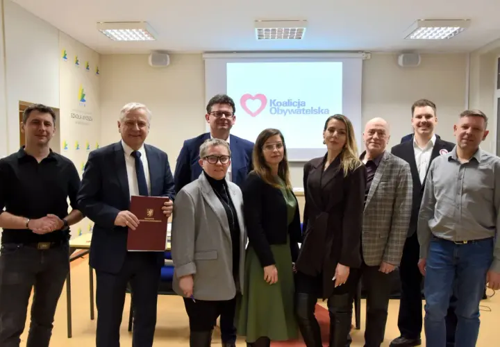 Grupa osób pozuje do zdjęcia przed ekranem z logo Koalicji Obywatelskiej.