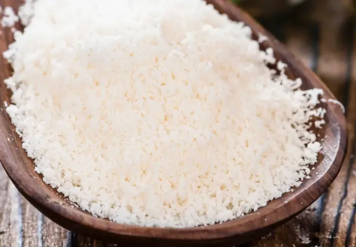 Cuchara de madera con rallado fino de parmesano vegano, listo para espolvorear sobre tu plato favorito.