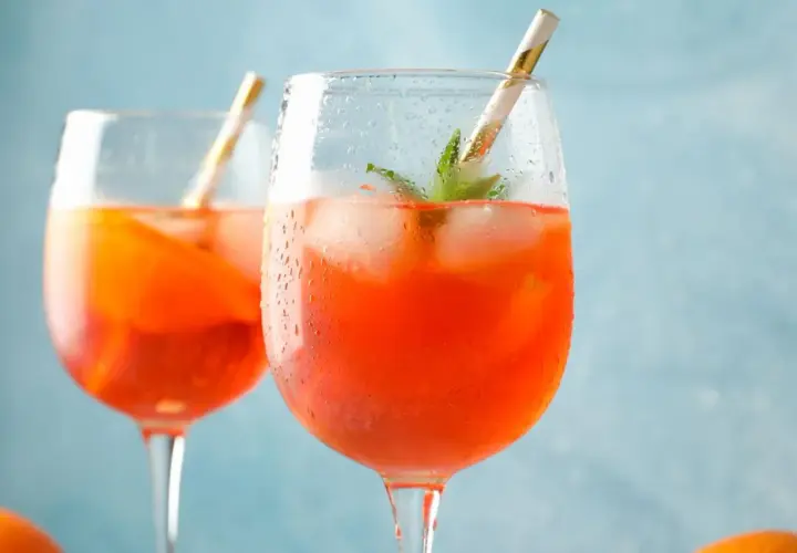 Zwei erfrischende Aperol Spritz mit Eis und Minze, bereit für einen sonnigen Nachmittag.