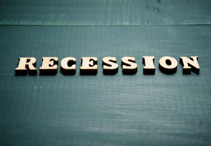 Drewniane litery układają słowo "RECESSION". To pojęcie ekonomiczne, które oznacza spadek aktywności gospodarczej.