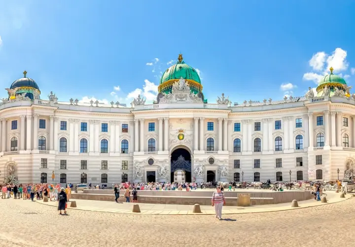 Majestatyczny pałac Sisi w Wiedniu, z zieloną kopułą i tłumem turystów na placu.