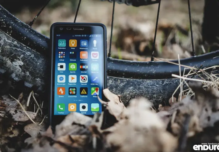 Szukasz alternatywy dla Endomondo za darmo? Smartfon z aplikacjami do śledzenia aktywności, jak Strava czy Locus Map, leży obok opony rowerowej.