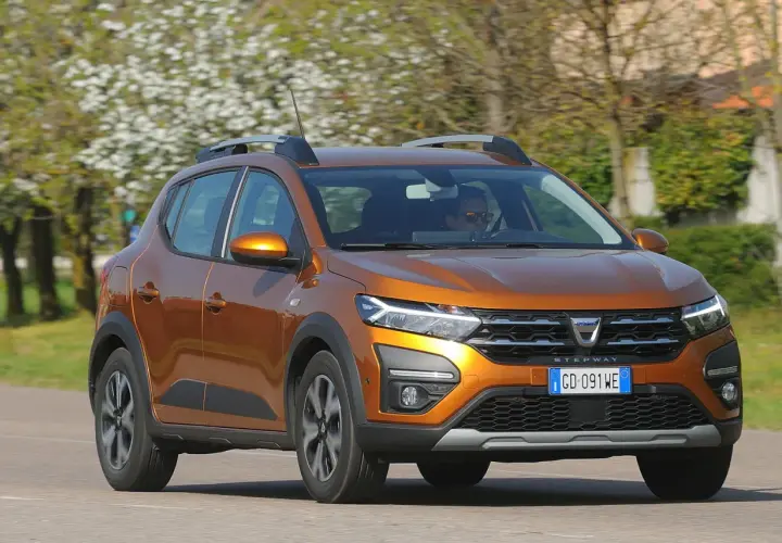 Dacia Sandero Stepway arancione in movimento, con alberi fioriti sullo sfondo. Nonostante i suoi pregi, alcuni difetti Dacia Sandero Stepway sono noti.