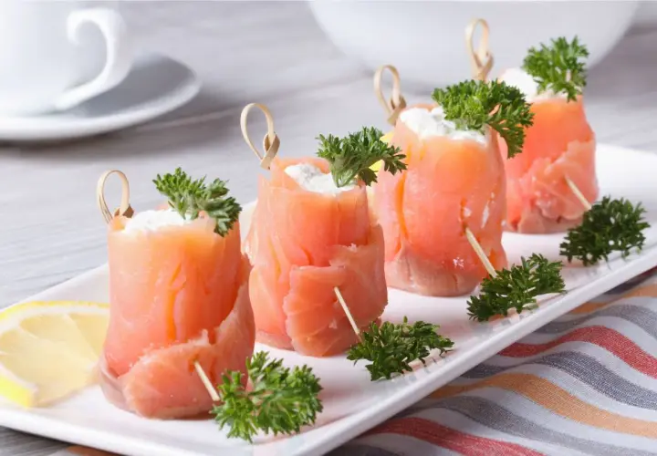 Rotolini di salmone affumicato con formaggio cremoso e prezzemolo, perfetti per ricette fredde.