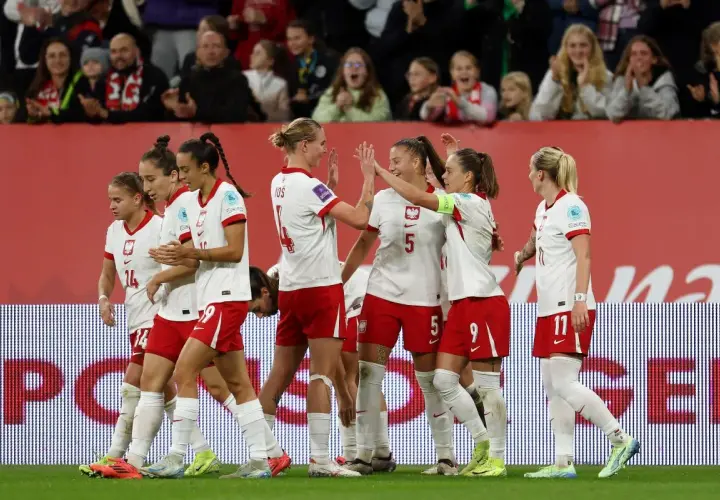 Piłkarki w biało-czerwonych strojach świętują sukces. To dumne polskie dania na boisku, pełne radości i sportowego ducha.