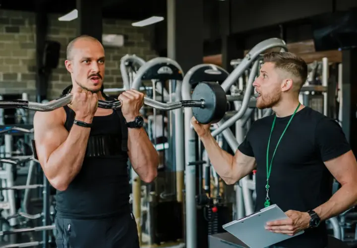 Trener instruuje klienta, jak wykonać ćwiczenie. Czy to superseria? Dowiedz się, co to jest i jak może pomóc w treningu.