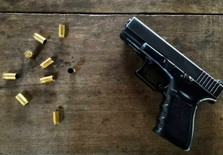 Czarny pistolet i łuski na drewnianym stole. Jaka broń na pozwolenie kolekcjonerskie?