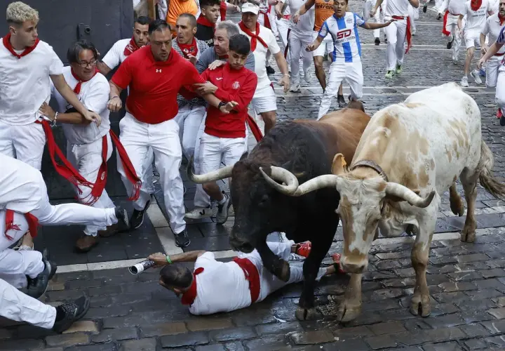 Hombres vestidos de blanco corren junto a toros de la ganadería Gregorio Garzón. Uno cae al suelo.