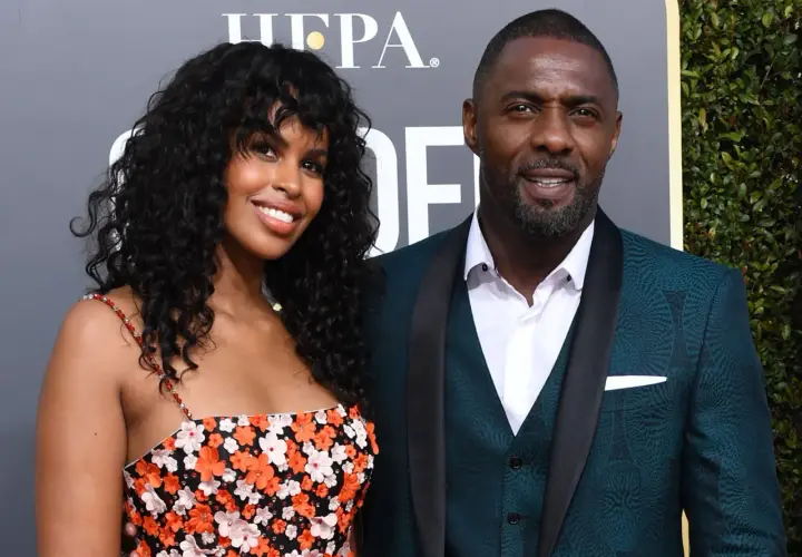 Idris Elba z żoną, Sabriną Dhowre, na czerwonym dywanie. Ona w kwiecistej sukience, on w eleganckim garniturze.