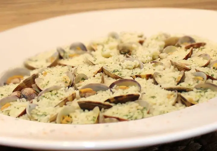Delicioso arroz con almejas, un plato de marisco cremoso y lleno de sabor, adornado con perejil fresco.