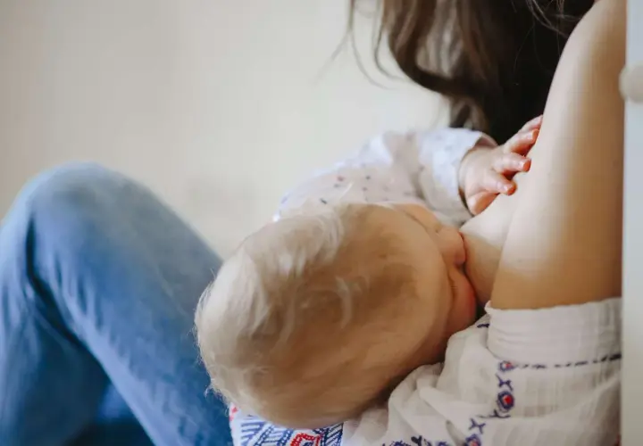Mamma allatta il suo bambino, dimostrando che si può allattare con la febbre. Un momento di amore e cura.