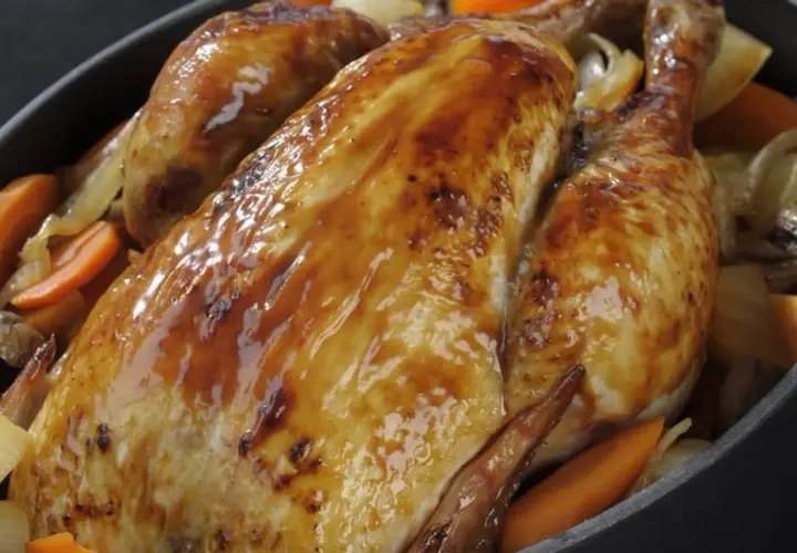 Un poulet rôti doré et juteux, accompagné de carottes et d'oignons. Un délice pour savoir quel vin avec un poulet rôti.