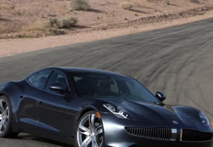 Elegancki, ciemny Fisker Karma na torze wyścigowym, gotowy do jazdy po pustynnych zakrętach.