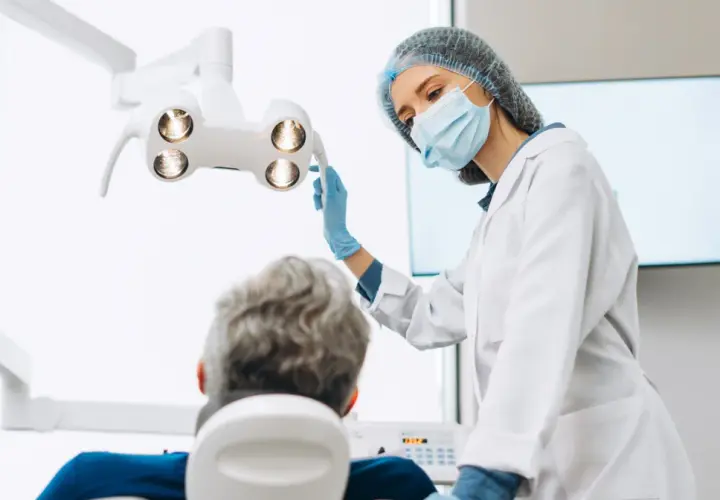 Dentystka w masce i rękawiczkach przygotowuje się do zabiegu. Pacjent siedzi na fotelu. Czy dentysta może wystawić L4?