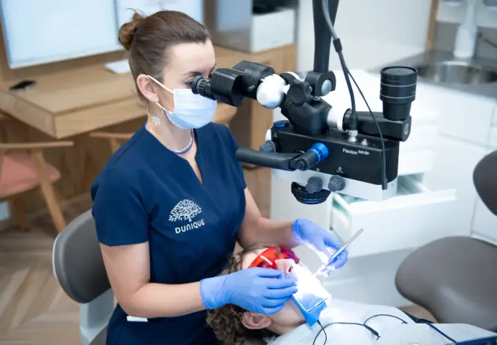 Doświadczony technik dentystyczny pracuje pod mikroskopem, dbając o każdy szczegół leczenia.