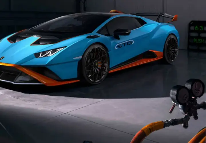 Niebieskie Lamborghini Huracán STO z pomarańczowymi akcentami w garażu.