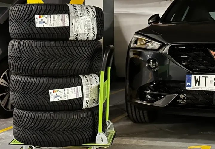 Cztery nowe opony Michelin CrossClimate 2, uznawane za najlepsze opony wielosezonowe, czekają na montaż w czarnym aucie.