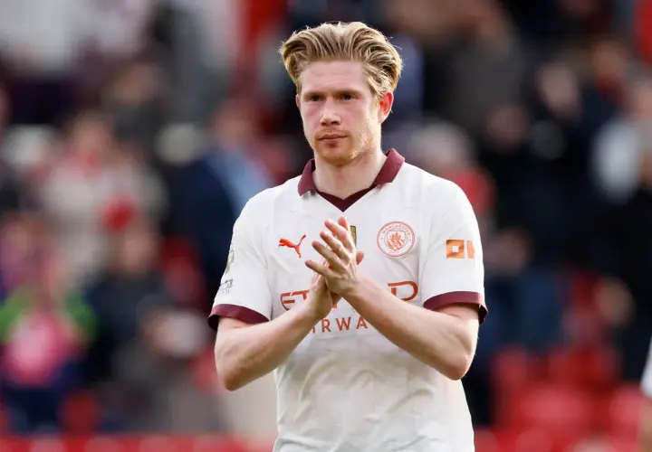 Kevin De Bruyne, w białej koszulce Manchesteru City, klaszcze w dłonie. Jego obecne drużyny to Manchester City.