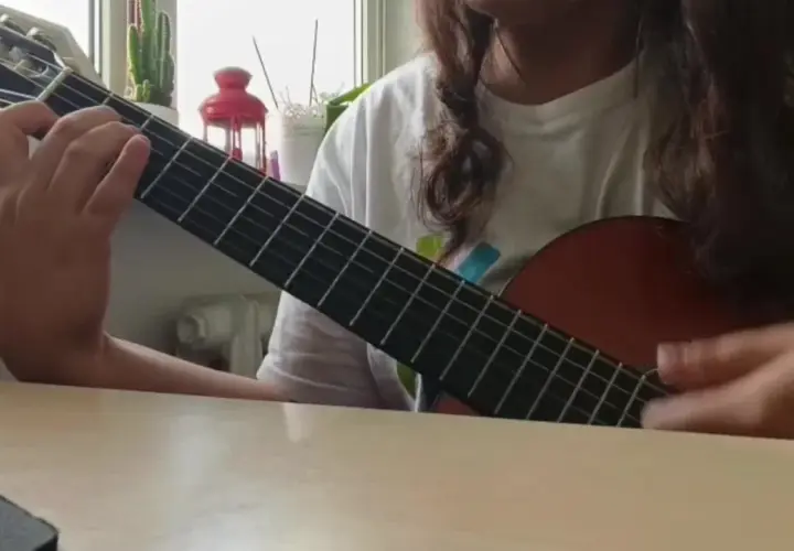 Osoba gra na gitarze klasycznej, ćwicząc znane utwory na gitarę klasyczną.