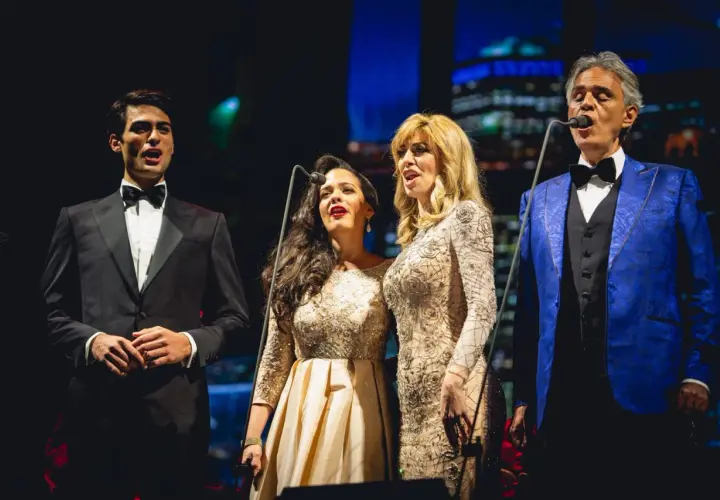 Andrea Bocelli śpiewa z synem i dwiema artystkami na scenie.