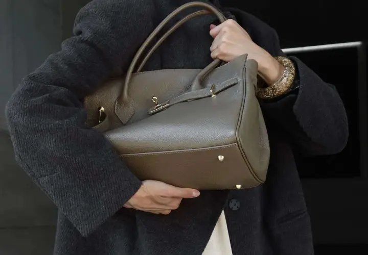 Elegancka, szara torebka na ramię z uchwytami i złotymi elementami. Idealnie wpisuje się w trendy, pokazując, jakie torebki są teraz modne.