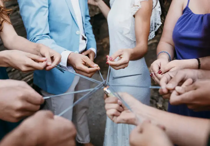 Manos sostienen bengalas formando un círculo, creando un ambiente festivo para juegos para bodas.