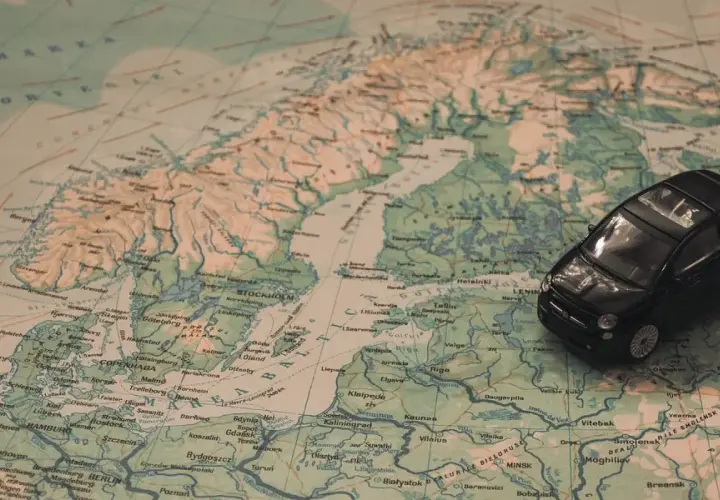 Czarny Fiat 500 na mapie Europy, planujący podróż na Mikołajki do Olsztyna.