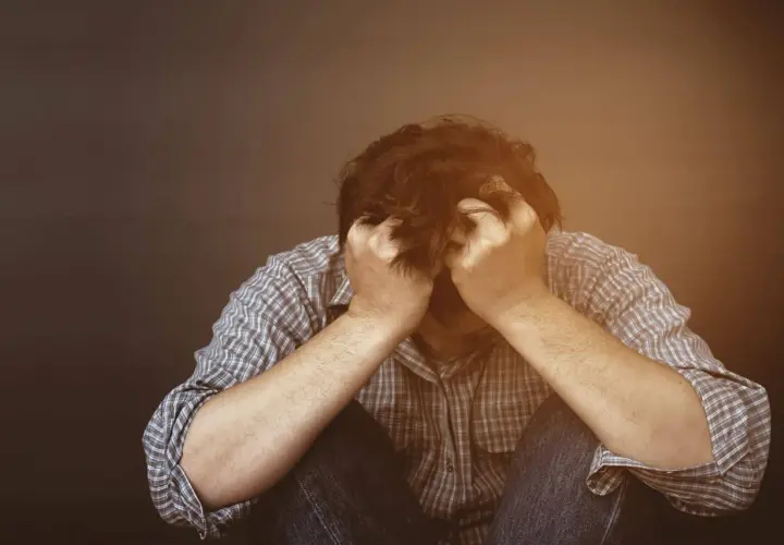 Mężczyzna w rozpaczy, trzymający się za głowę. Może to być symbol trudności związanych z uzyskaniem zaświadczenia od psychologa do rozwodu.