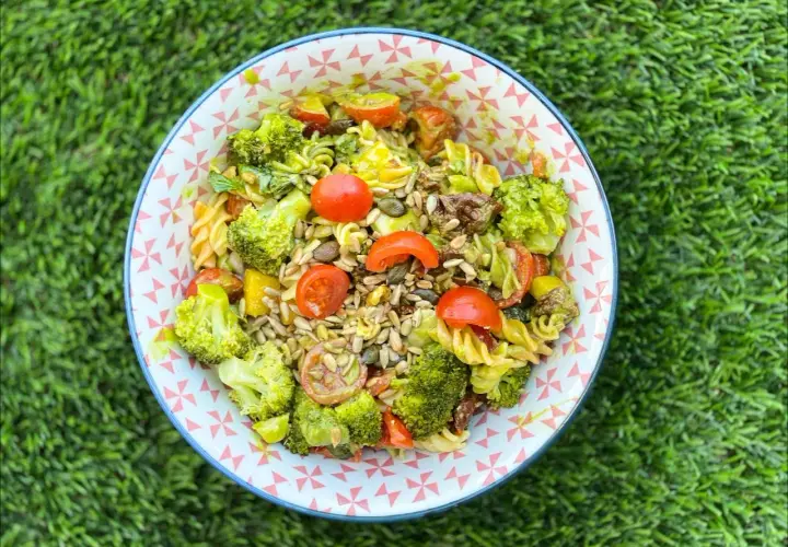 Ensalada de pasta con brócoli, tomates cherry y semillas. Los ingredientes frescos y coloridos la hacen irresistible.