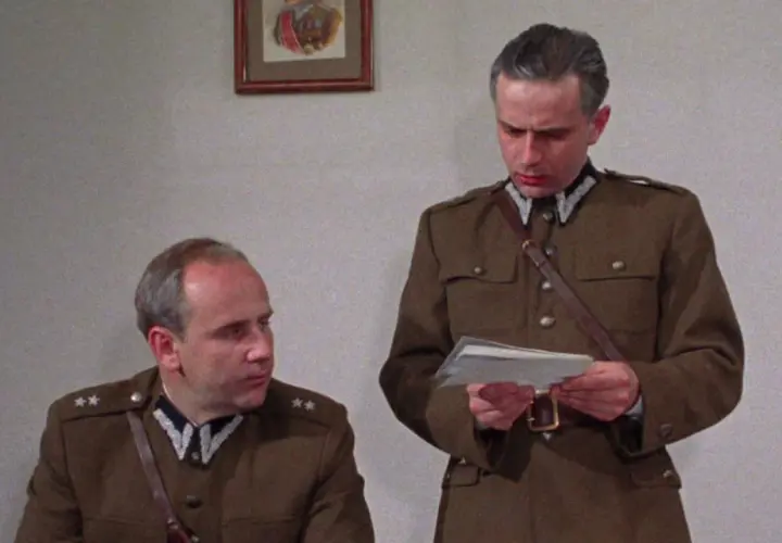 Dwóch mężczyzn w mundurach wojskowych, jeden czyta dokument. Scena z filmu "Pogranicze w ogniu obsada".