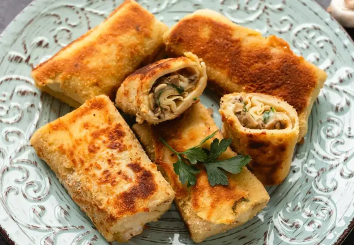 Chrupiące krokiety z pieczarkami i serem, podane na ozdobnym talerzu. W środku widoczny farsz z grzybów i ziół.