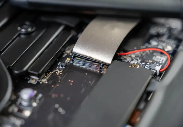 Nahaufnahme eines Motherboards, bereit für die m2 ssd installieren. Ein silbernes Kabel ist mit einem Anschluss verbunden.