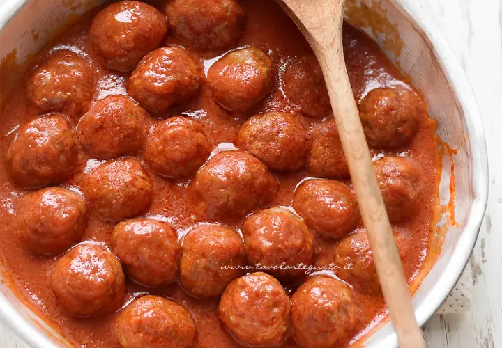 Succulente polpette in padella, immerse in un sugo rosso invitante, pronte per essere gustate.