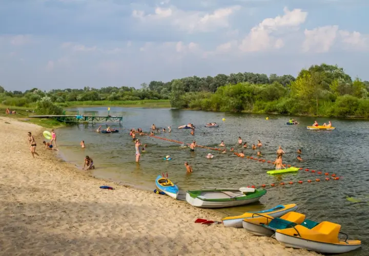 Wola Uhruska tętni życiem. Ludzie kąpią się, pływają na łódkach i relaksują na piaszczystej plaży.
