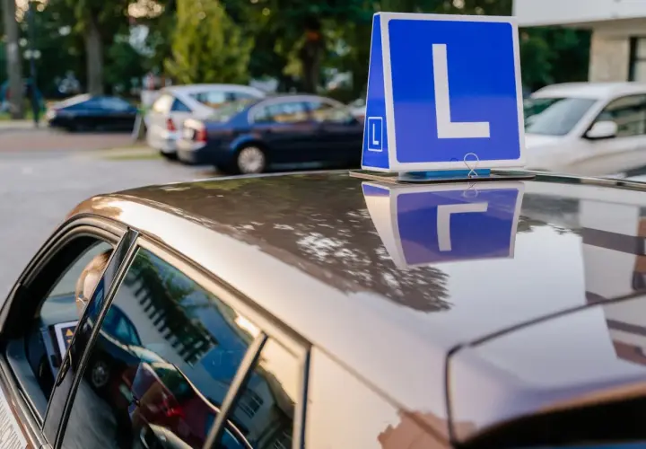 Niebieska tablica z literą "L" na dachu samochodu nauki jazdy.