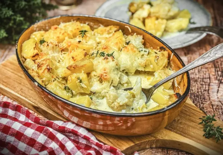 Herzhafter blumenkohl auflauf mit Kartoffeln und Käse überbacken, dampfend in einer Auflaufform.