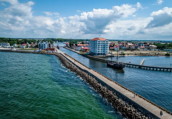 Port w Darłowie z falochronem, statkiem pirackim i nowoczesnym budynkiem. Atrakcje turystyczne na wyciągnięcie ręki.