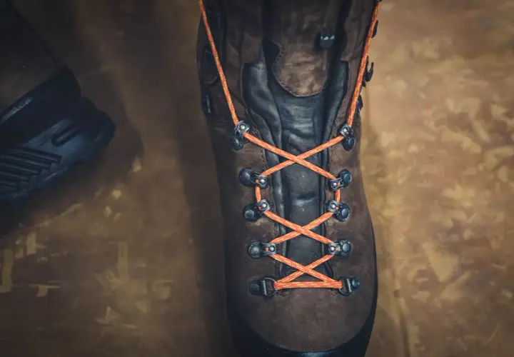 Close-up of a brown hiking boot with bright orange laces tied in a parallel lacing pattern, ready for adventure.