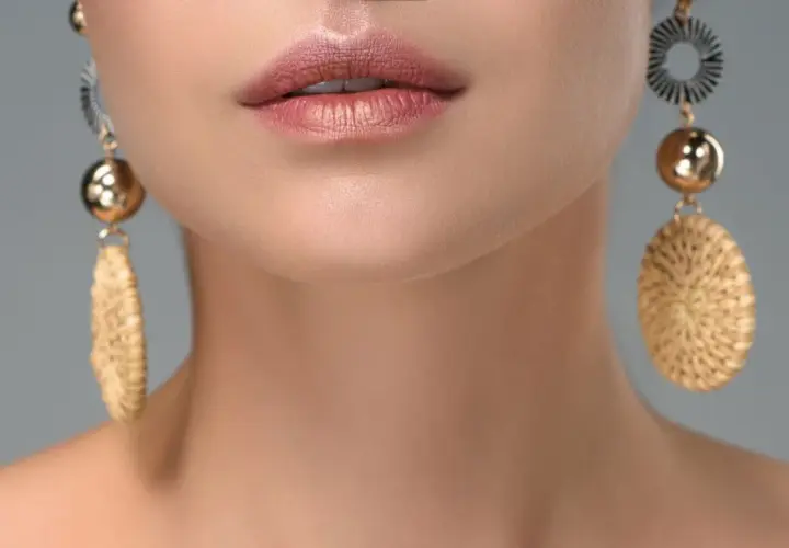 Labios maquillados y pendientes dorados con detalles que recuerdan a tipos de piedras preciosas.