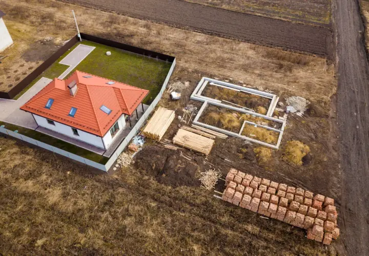 Budowa domu na działce 3 klasy ziemi. Fundamenty, drewno i cegły czekają na realizację warunków zabudowy.