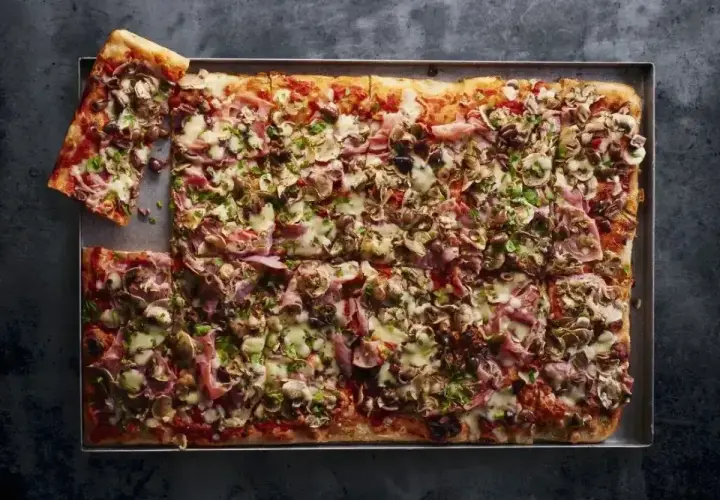 Pyszna pizza domowa przepis na blachę, obficie posypana pieczarkami, szynką i serem. Idealna na rodzinne spotkanie.