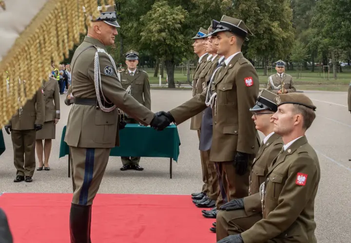 Podporucznik skrót. Uroczystość wręczenia odznaczeń wojskowych. Dwóch oficerów w mundurach ściska sobie dłonie.