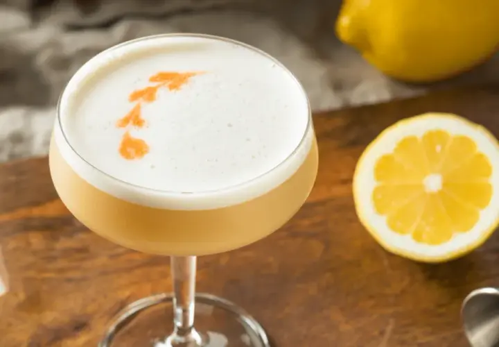 En drink med fluffigt kokosskum och en citronskiva bredvid.