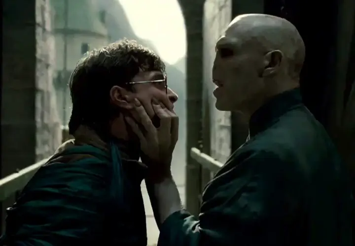 Ralph Fiennes jako Voldemort grozi Harry'emu Potterowi, chwytając go za twarz.