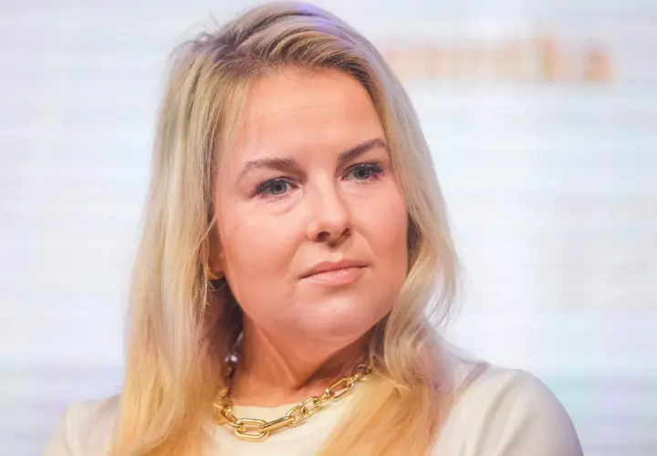 Kamila Kalinczak z blond włosami i złotym naszyjnikiem, patrzy w bok.