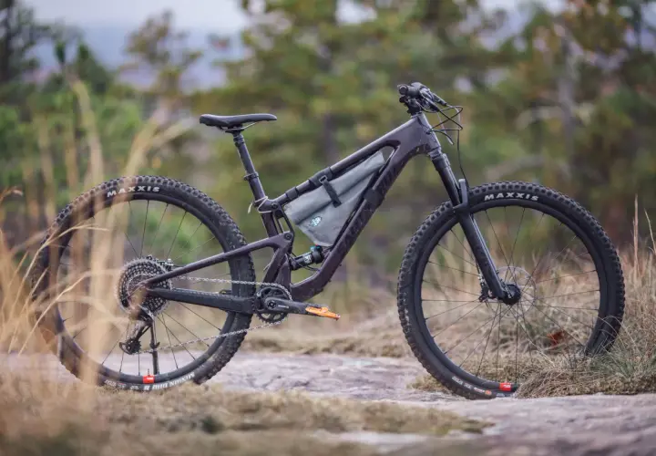 A dark purple Santa Cruz Tallboy 4 mountain bike rests on rocky terrain, ready for an adventure.